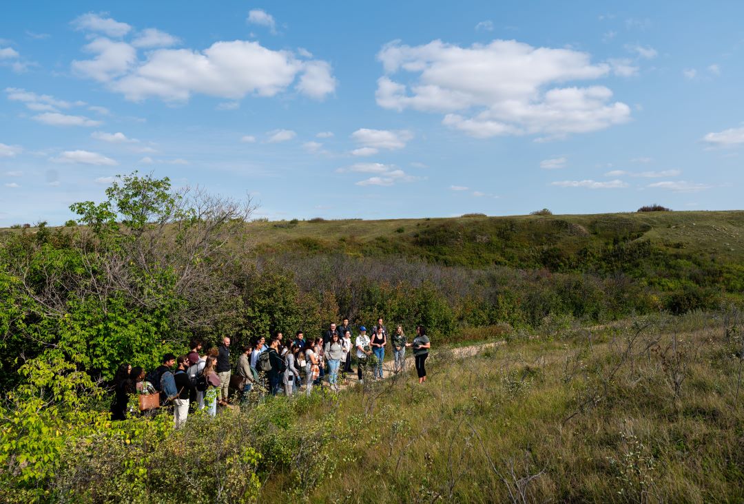 A group of about 20 Law students stands on a hillside at Wanuskewin Heritage Park in Saskatoon. 