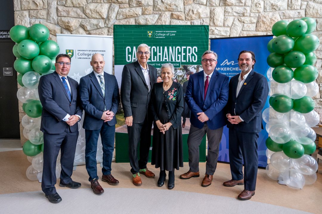 Men and women in business attire posing for a group photo in the USask College of Law 