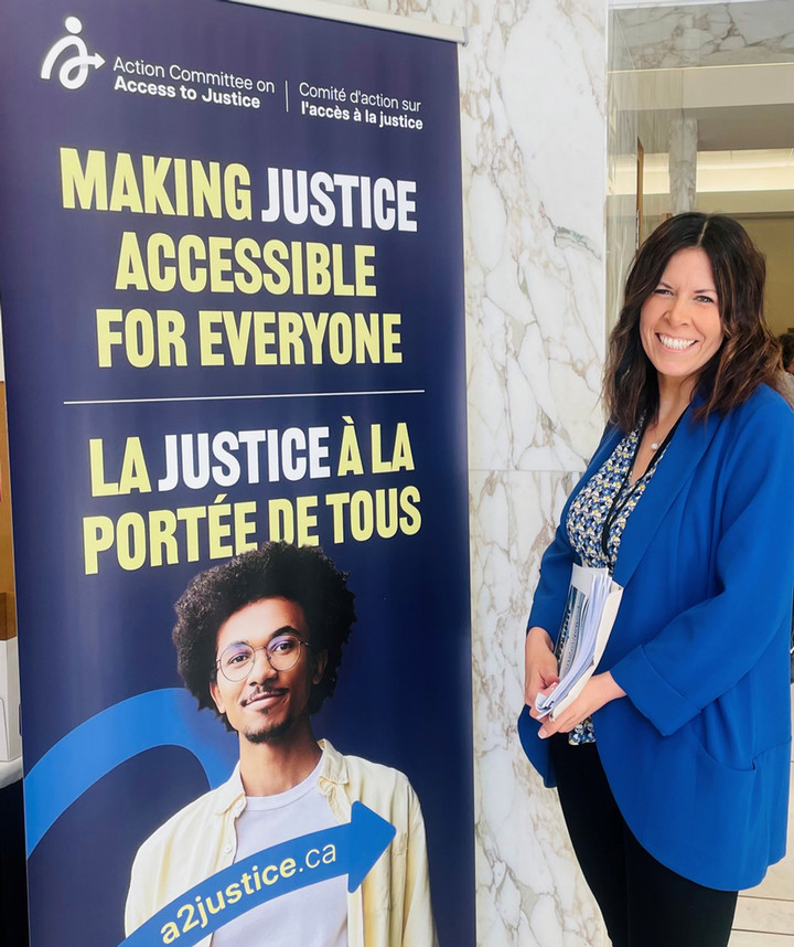 Brea Lowenberger standing beside an access to justice banner