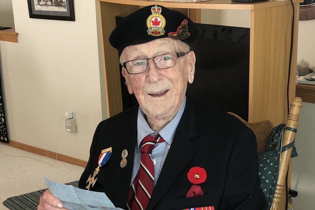 A photo of a smiling elderly gentleman wearing a Legion beret and dark blue suit jacket with several medals on his chest.